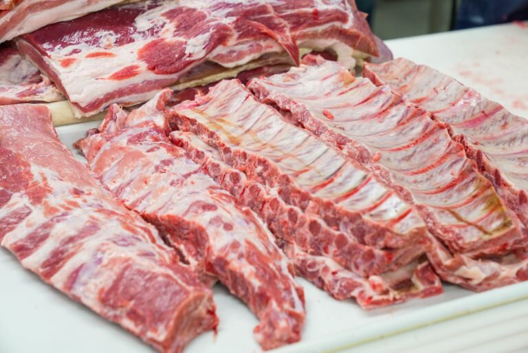 Coaste de porc glazurate, gătite lent, tăiate pe un fund de lemn, cu crustă lucioasă și închisă la culoare
